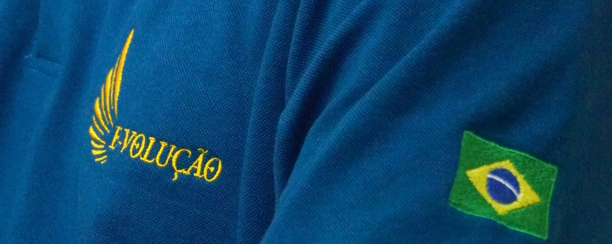 Detalhe do uniforme da E-volução com o logo bordado e a bandeira do Brasil na manga