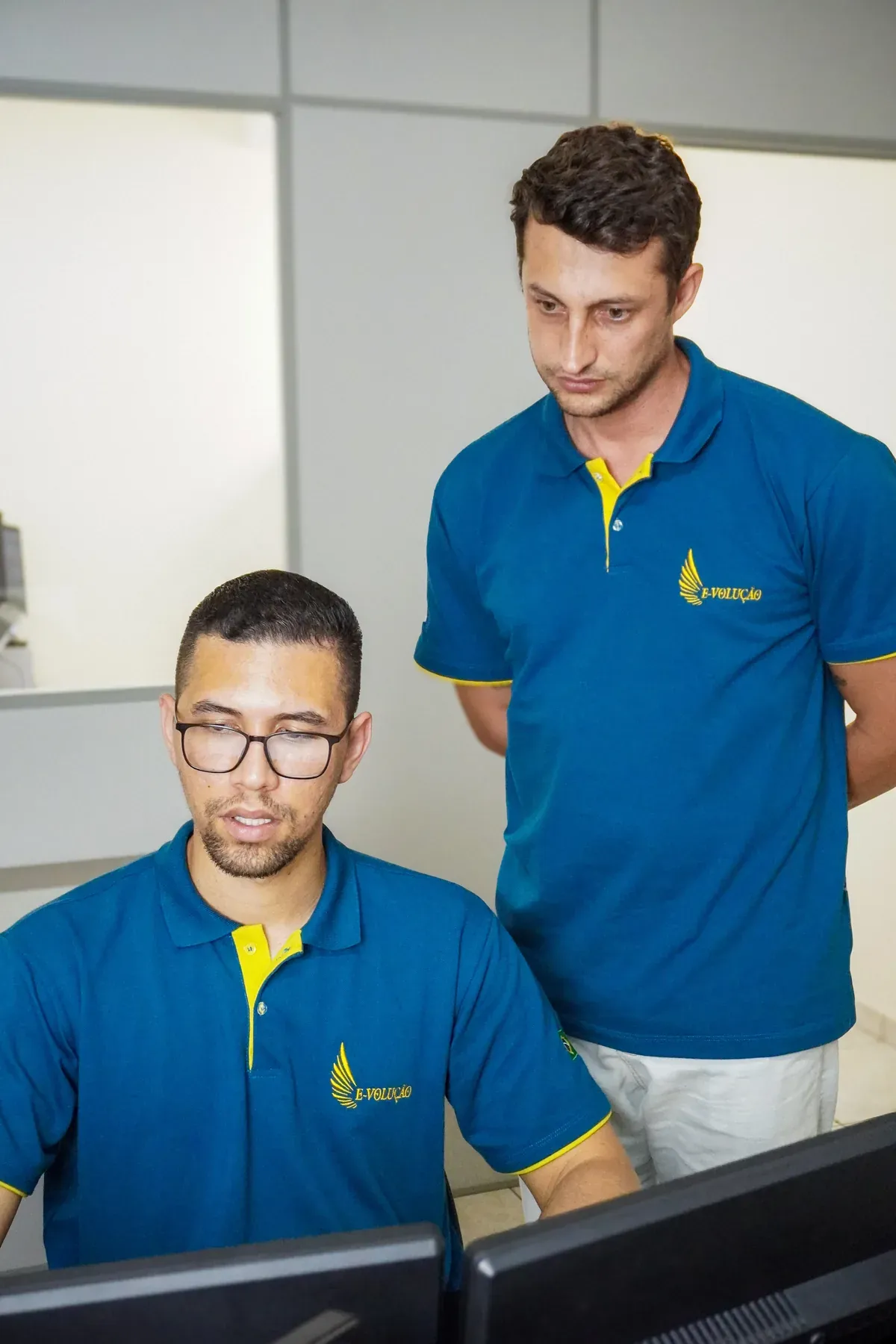 Dois integrantes da equipe da E-volução revisando um trabalho no computador