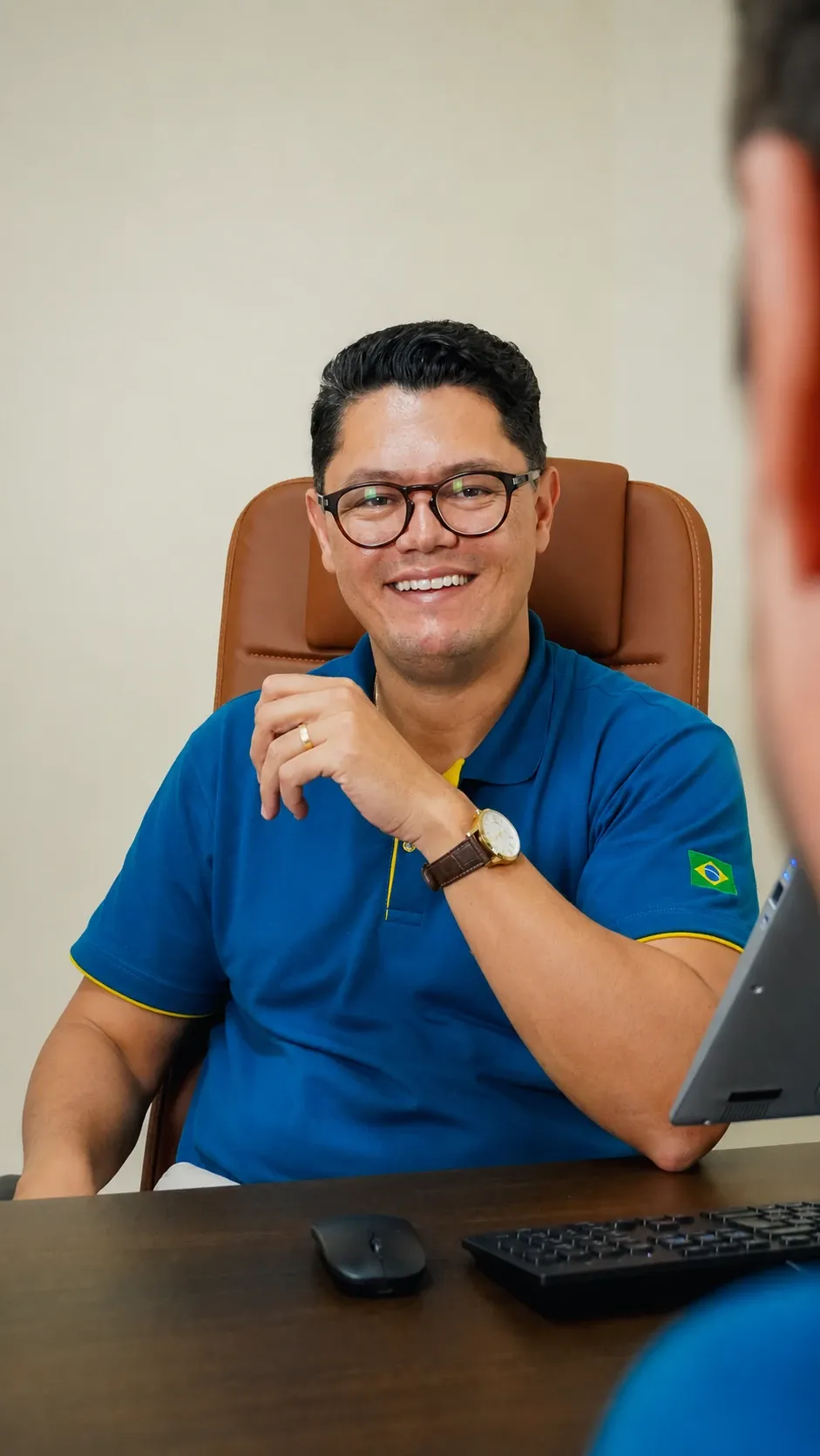 Francklin sorrindo durante atendimento na mesa do escritório